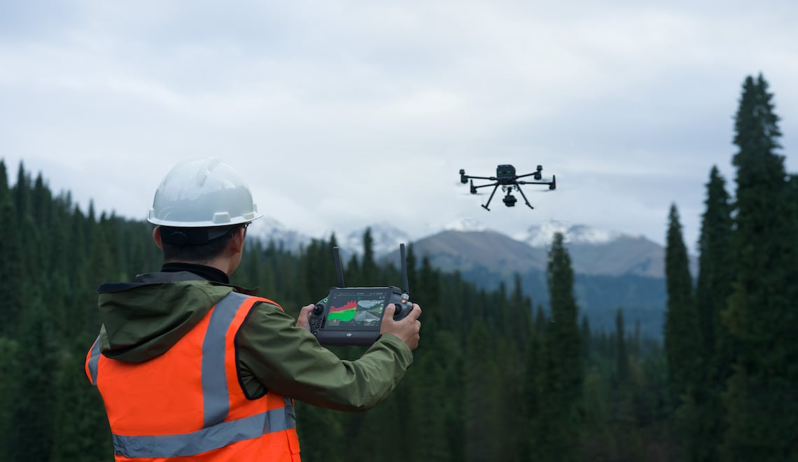 Survey operator flying a LiDAR-equipped drone in mountainous terrain